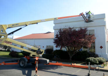 Bear Rental employee putting up Christmas lights with a tow-behind lift