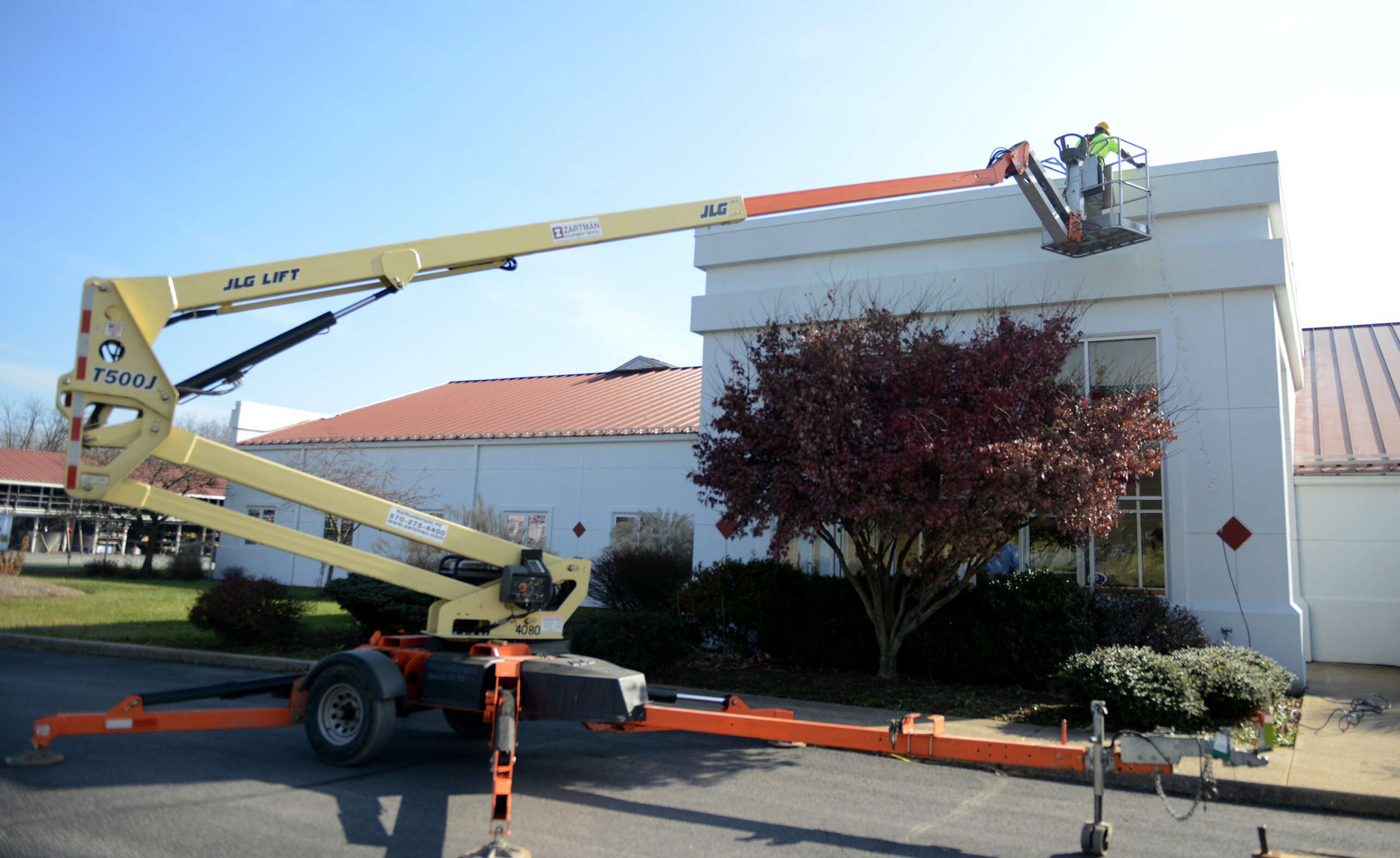 Bear Rental employee putting up Christmas lights with a tow-behind lift